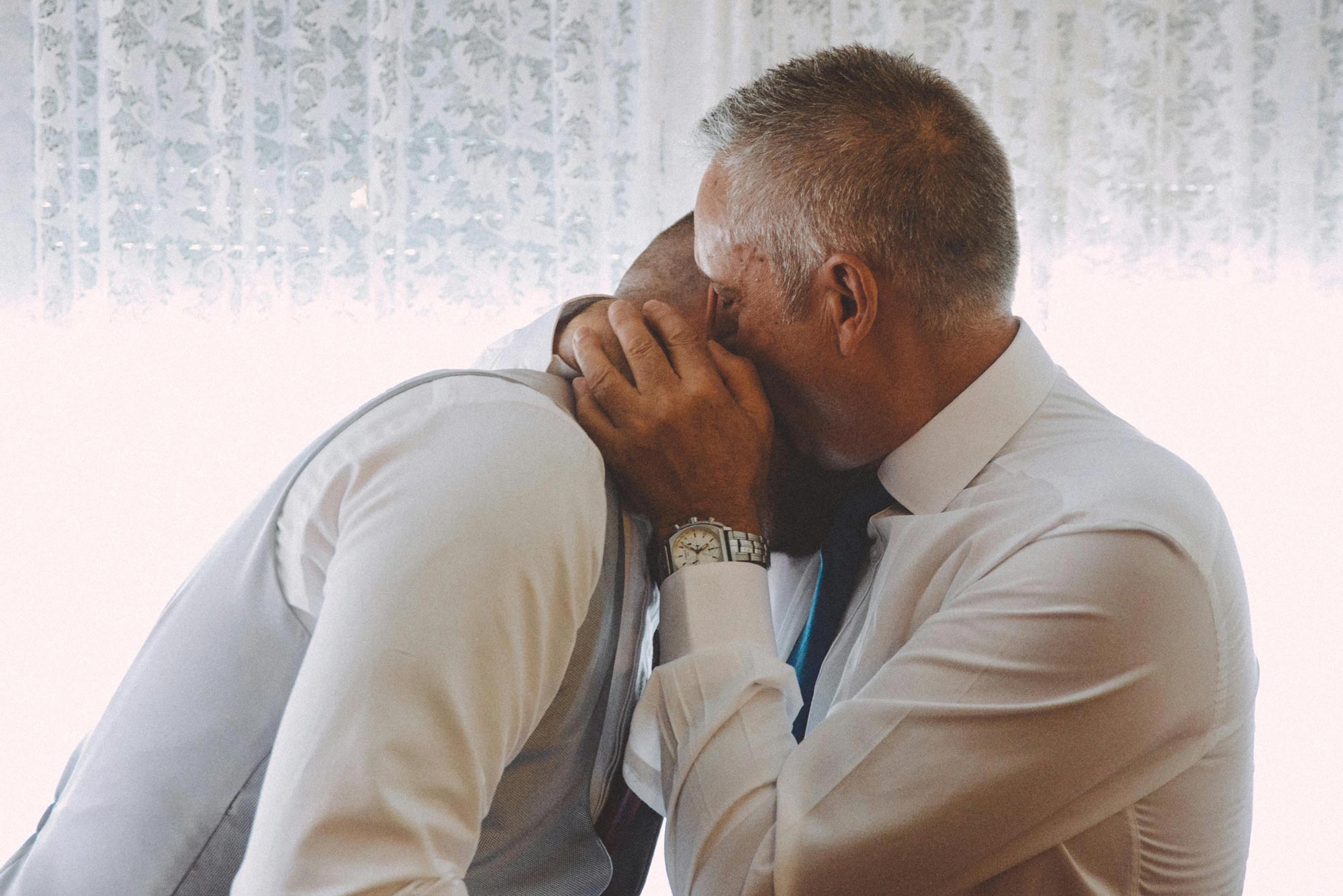 Father embracing son behind the scenes at a wedding